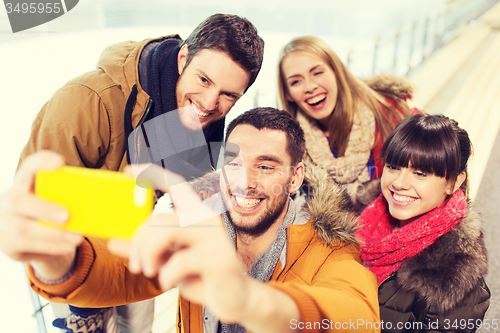 Image of happy friends with smartphone on skating rink