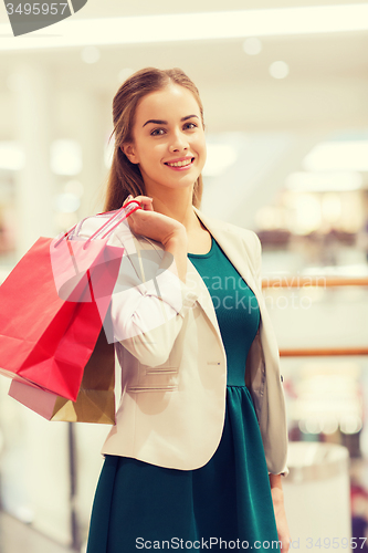 Image of happy young woman with shopping bags in mall