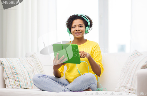 Image of happy african woman with tablet pc and headphones