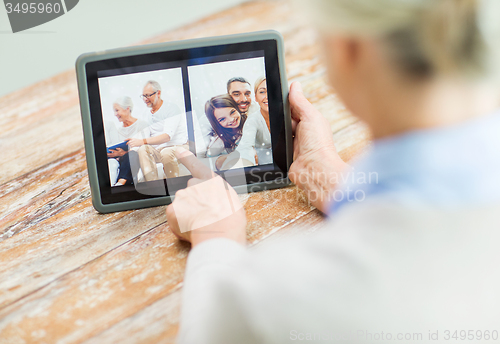 Image of senior woman with family photo on tablet pc screen