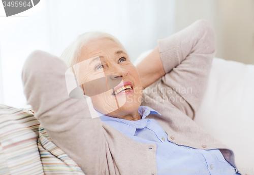 Image of happy senior woman resting on sofa at home