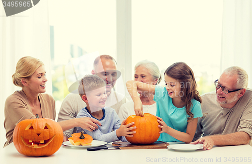 Image of happy family sitting with pumpkins at home