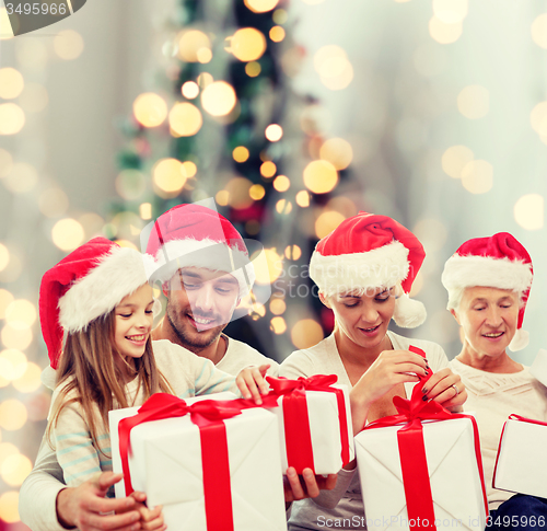 Image of happy family in santa helper hats with gift boxes