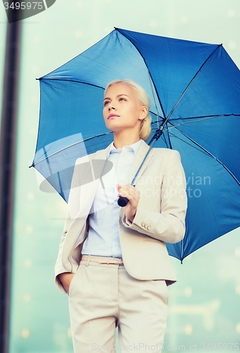 Image of young serious businesswoman with umbrella outdoors