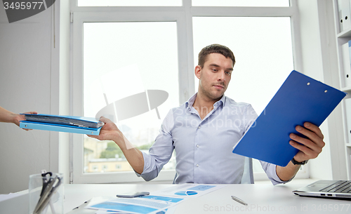 Image of businessman taking papers from secretary in office