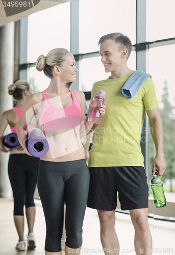 Image of smiling couple with water bottles in gym