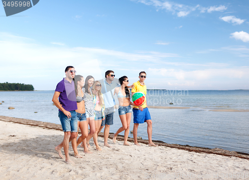 Image of group of happy friends walking along beach