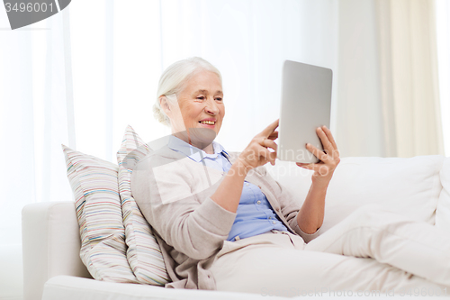 Image of happy senior woman with tablet pc at home