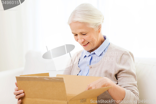 Image of happy senior woman with parcel box at home