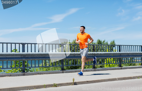 Image of smiling young man running at summer seaside