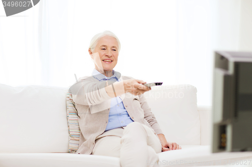 Image of happy senior woman watching tv at home