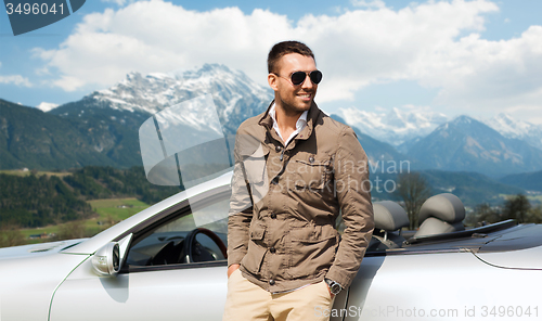 Image of happy man near cabriolet car over mountains