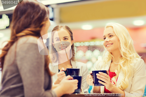 Image of smiling young women with cups in mall or cafe