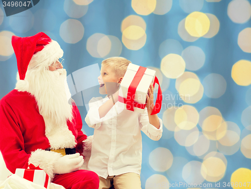 Image of smiling little boy with santa claus and gifts