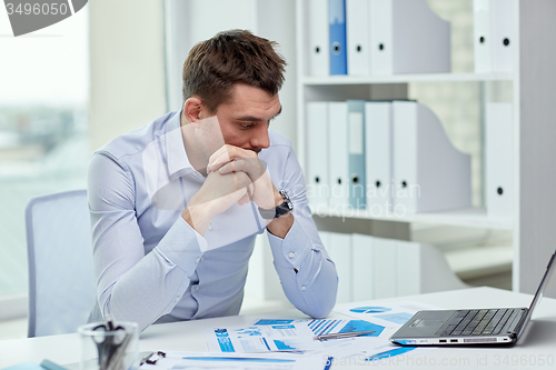 Image of stressed businessman with laptop and papers