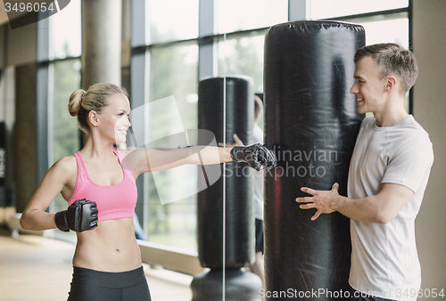 Image of smiling woman with personal trainer boxing in gym