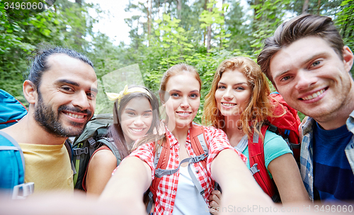 Image of friends with backpack taking selfie in wood