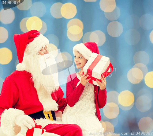 Image of smiling little girl with santa claus and gifts