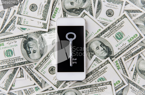 Image of close up of smartphone with key and dollar money