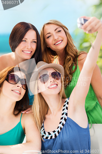 Image of girls taking photo in cafe on the beach