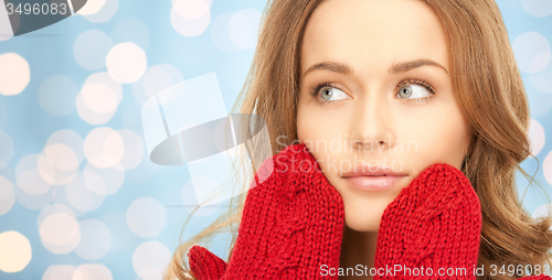 Image of happy young woman in red mittens over blue lights