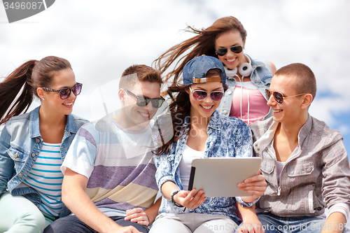 Image of group of smiling teenagers looking at tablet pc