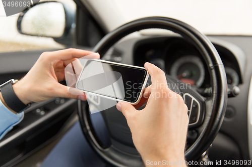 Image of close up of man hand with smartphone driving car