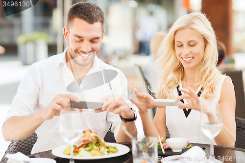 Image of happy couple with smatphone photographing food