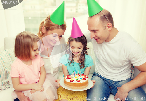 Image of smiling family with two kids in hats with cake