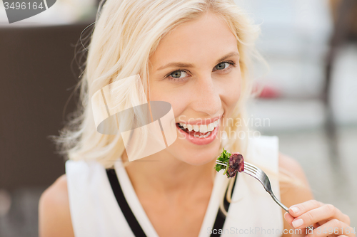 Image of happy woman eating dinner at restaurant terrace