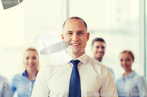 Image of smiling businessman with colleagues in office