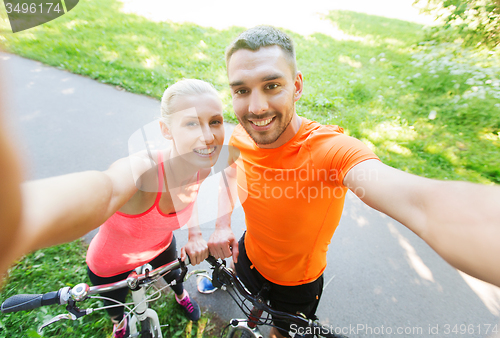 Image of couple with bicycle taking selfie outdoors