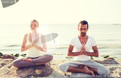 Image of smiling couple making yoga exercises outdoors