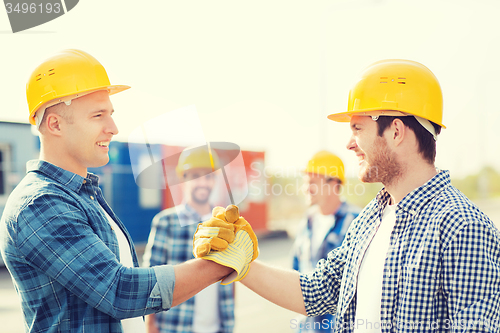 Image of group of smiling builders in hardhats outdoors