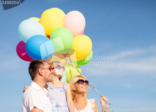 Image of happy family with colorful balloons outdoors