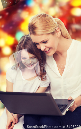 Image of smiling mother and little girl with laptop