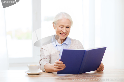 Image of happy smiling senior woman reading book at home