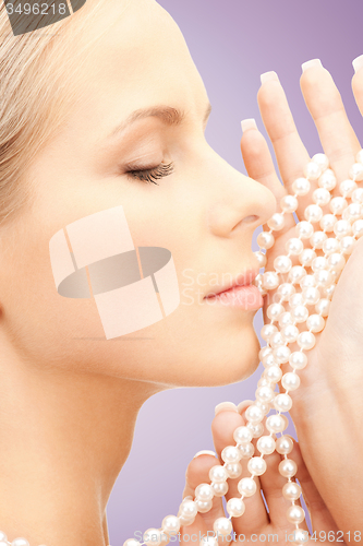 Image of beautiful woman with sea pearls beads over violet