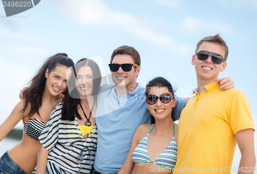 Image of group of happy friends hugging on beach