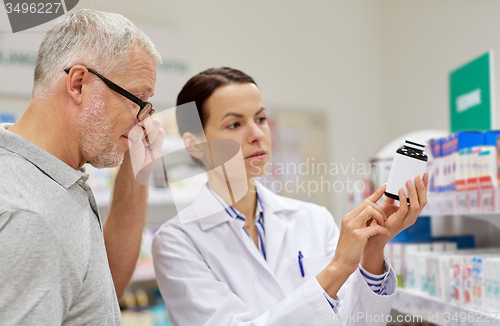 Image of pharmacist showing drug to senior man at pharmacy