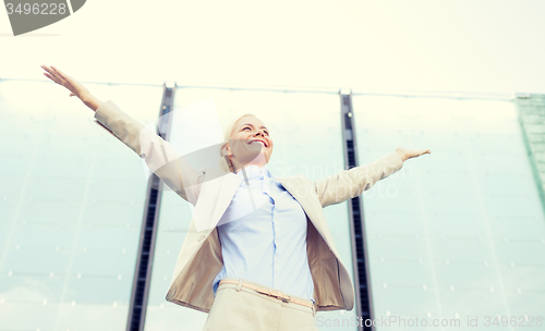 Image of young smiling businesswoman over office building