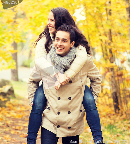 Image of smiling couple having fun in autumn park