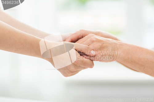 Image of close up of senior and young woman holding hands