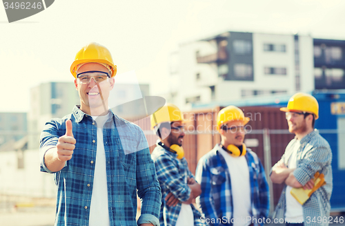 Image of group of smiling builders in hardhats outdoors
