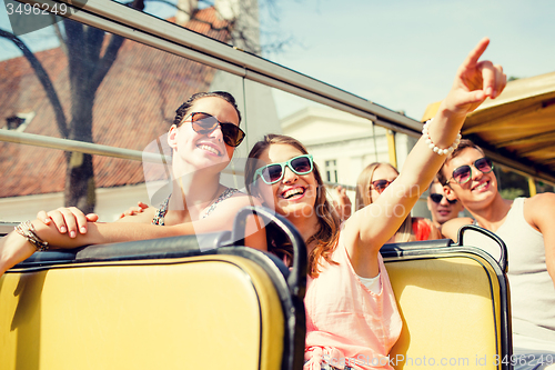 Image of group of smiling friends traveling by tour bus