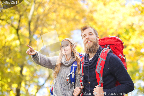 Image of smiling couple with backpacks hiking over autumn