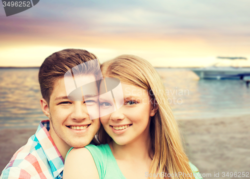 Image of smiling couple hugging over beach background