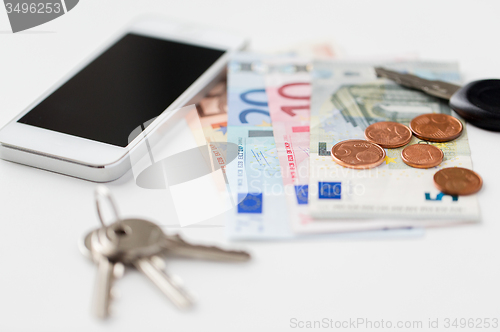 Image of close up of smartphone, money and keys on table