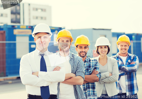 Image of group of smiling builders in hardhats outdoors