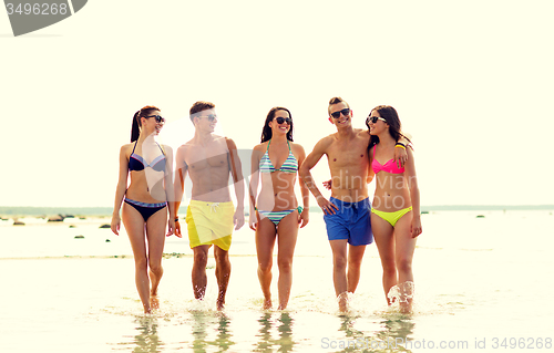 Image of smiling friends in sunglasses on summer beach